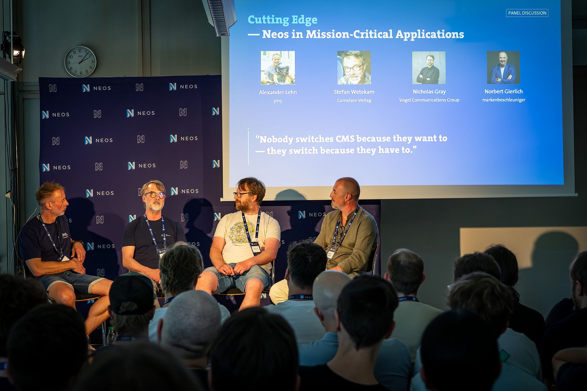 Vier Personen sitzen im Rahmen einer Panel-Diskussion auf einer Bühne